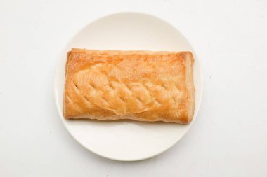Image of Appetizing closely packed fresh square shaped puff pastry biscuit snacks with puffed crispy golden brown crust layersa In a white plate  isolate on a white backdrop. 