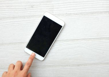 Asyalı kadını bir düğme kullanarak ya da akıllı telefonun ekranına dokunarak beyaz ahşap bir arka planda izole edin. teknoloji konsepti iletişim ve iş