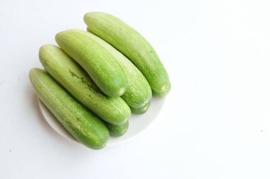 Taze çiğ organik salatalıkları (salatalık satisi) beyaz seramik bir tabakta yeşil sebzeleri kapayın. Sağlıklı meyve, sebze ve yiyecek kavramı.