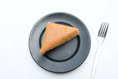 Üst manzara beyaz arka planda siyah seramik tabakta çırpılmış kremalı iştah açıcı vanilyalı şifon pasta. Hafif, kabarık, renkli sünger keki. tatlı konsepti