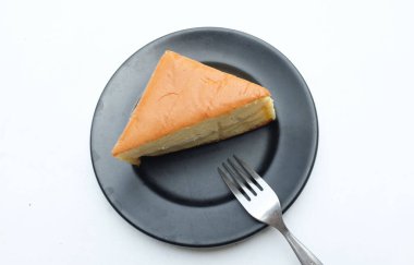 Üst manzara beyaz arka planda siyah seramik tabakta çırpılmış kremalı iştah açıcı vanilyalı şifon pasta. Hafif, kabarık, renkli sünger keki. tatlı konsepti