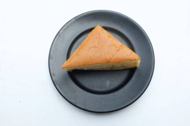 Üst manzara beyaz arka planda siyah seramik tabakta çırpılmış kremalı iştah açıcı vanilyalı şifon pasta. Hafif, kabarık, renkli sünger keki. tatlı konsepti