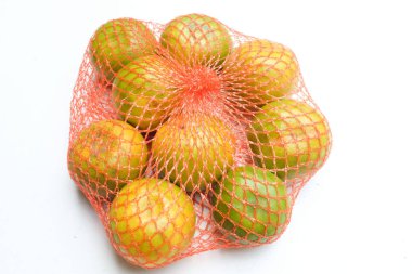 Taze, iştah açıcı portakallar plastik bir torba içinde meyve ya da beyaz bir arkaplanda izole edilmiş bir ağ torbası taşıyın.