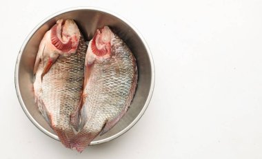  Taze çiğ Tilapia balığı Oreochromis niloticus (Linn.) Paslanmaz çelik bir leğende, beyaz bir arka planda izole edilmiş. Yemek malzemelerini alın. Sağlıklı beslenmeye hazırlanın.