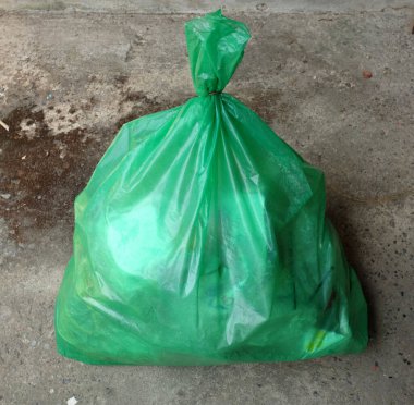Bir yeşil çöp torbası yerde yatıyordu. Büyük plastik torba atığı yığını. Kokuşmuş çöp yığını yeşil çanta. Kirli atık çöplüğü kokulu çöp. Konsept çevre koruma, atık yönetimi ve çevre