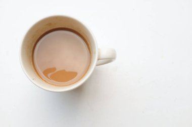 Beyaz fincanda servis edilen sıcak kahvenin üst görüntüsü beyaz arka planda izole edilmiş Asyalı bir kadının elinde. Kadın kahve içiyor, sabah rutini. Yiyecek ve içecek konsepti