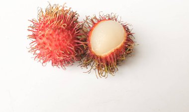 Taze olgun kırmızı rambutanlar (Nephelyum Lappaceum) bütün ve yarım ve yeşil yaprak beyaz bir arka planda izole edilir. Rambutan kırmızı kabuklu, beyaz etli, kahverengi tohumlu bir meyvedir. Tatlı bir tadı var.,