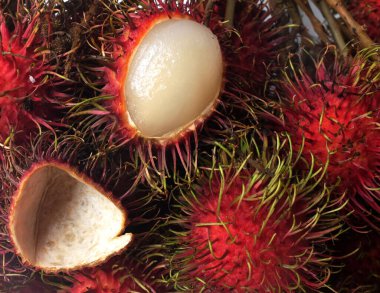 Taze olgun kırmızı rambutanları (Nephelyum Lappaceum) bir bütün ve yeşil yaprakları beyaz bir arka planda izole eder. Rambutan kırmızı kabuklu, beyaz etli, kahverengi tohumlu bir meyvedir. Tatlı bir tadı var.,