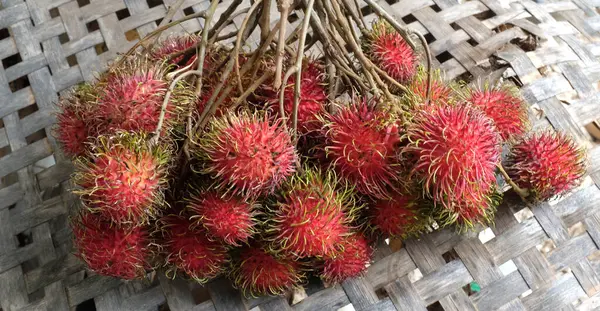 Taze olgun kırmızı rambutanları (Nephelyum Lappaceum) bir bütün ve yeşil yaprakları beyaz bir arka planda izole eder. Rambutan kırmızı kabuklu, beyaz etli, kahverengi tohumlu bir meyvedir. Tatlı bir tadı var.,