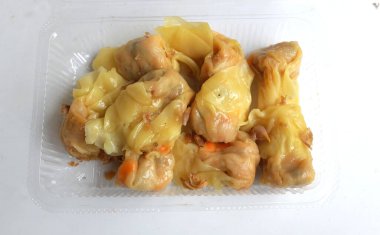 Siu Mai, Shumai, Çin buğulamalı hamur tatlısı, soya soslu şeffaf plastik bir kutunun içinde, beyaz bir arka planda izole edilmiş.