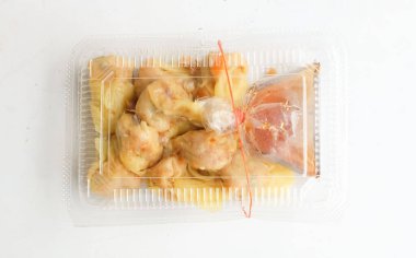 Appetizing a Siu Mai, Shumai, Chinese steamed dumplings, dim sum in a In a clear plastic box container with soy sauce, isolated on a white backdrop clipart