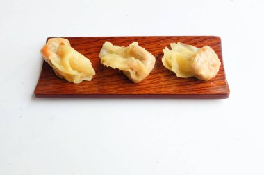 Shumai ya da Çin Buharlı Hamur köftesi, Wonton derili köfte, soya soslu ahşap bir tabakta servis edilen buharlı domuz köftesi, beyaz bir zeminde izole edilmiş çubuklar.
