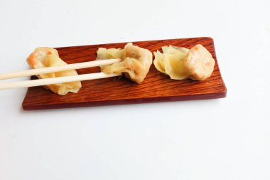 woman Using chopsticks to hold  a Shumai or Chinese Steamed Dumpling,meatball dumpling with wonton skin,Steamed Pork Dumpling  served in a wooden dish with soy sauce, chopsticks isolated on a white backdrop clipart