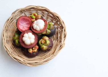 Taze, sulu, sulu, mangosteen meyveler (Garcinia mangostana L.) Tüm mangosteen ve ahşap bir sepette ikiye kesilmiş, beyaz bir zemin üzerinde Meyve Kraliçesi olarak bilinir.