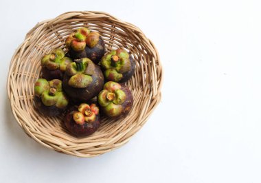 Taze, sulu, sulu, mangosteen meyveler (Garcinia mangostana L.) Tüm mangosteen ve ahşap bir sepette ikiye kesilmiş, beyaz bir zemin üzerinde Meyve Kraliçesi olarak bilinir.