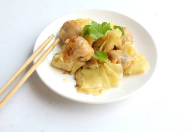 woman Using chopsticks to holda Shumai or Chinese Steamed Dumpling,meatball dumpling with wonton skin,Steamed Pork Dumpling  served in a white dish isolated on a white backdrop clipart