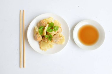 Shumai ya da Çin Buharlı Hamur köftesi, Wonton derili köfte, soya soslu beyaz bir tabakta servis edilen domuz etli börek ve beyaz bir arkaplanda izole edilmiş soya sosu.