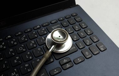 Tıbbi steteskop ve dizüstü bilgisayar, gözlük doktorun masasında. Çevrimiçi tıp, e-sağlık eğitimi, küresel ağ hakkında tıbbi iş raporu. Sağlık ve tıp geçmişi. 