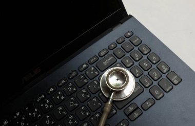 Tıbbi steteskop ve dizüstü bilgisayar, gözlük doktorun masasında. Çevrimiçi tıp, e-sağlık eğitimi, küresel ağ hakkında tıbbi iş raporu. Sağlık ve tıp geçmişi. 