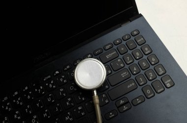 Tıbbi steteskop ve dizüstü bilgisayar, gözlük doktorun masasında. Çevrimiçi tıp, e-sağlık eğitimi, küresel ağ hakkında tıbbi iş raporu. Sağlık ve tıp geçmişi. 