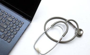 Tıbbi steteskop ve dizüstü bilgisayar, gözlük doktorun masasında. Çevrimiçi tıp, e-sağlık eğitimi, küresel ağ hakkında tıbbi iş raporu. Sağlık ve tıp geçmişi. 