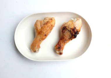 Sulu ve lezzetli ızgara tavuk bacağı ya da but ızgara bbq tavuk bacağı, kızarmış tavuk bacağı beyaz bir arkaplanda izole edilmiş seramik bir yemek.