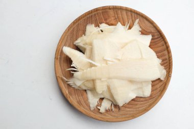 Taze dilimlenmiş bambu filizi, ahşap tabakta bambu filizi beyaz bir arka planda izole edilir. Yeraltı rizomlarından kırılan yenilebilir bambu. Sebzeler ve sağlıklı yiyecekler.