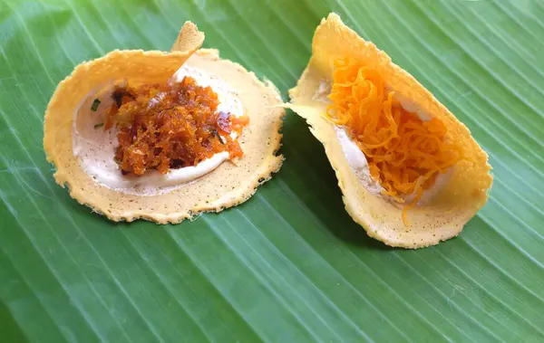 stock image  Khanom Bueang,Thai crispy pancakes. White cream made from egg whites mixed with sugar, beaten until smooth like whipping cream. Garnish with foi thong or fried shredded shrimp on a banana leaf