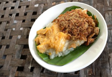 Thai dessert, Appetizing Sweet sticky rice with egg custard ,dried fishin the white plate isolate on a Woven bamboo floor backdrop clipart