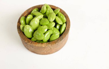 Acı fasulye, bükülmüş fasulye, kokulu fasulye, sato, petai veya pakria, (parkia speciosa) beyaz bir zemin üzerinde izole edilmiş ahtan bir kasede yemek pişirmeye hazırlan. Tayland ve Asya malzemeleri için bitkiler. .