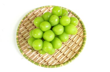 Bir demet taze Sweet Green Shine Muscat (Vitis vinifera) üzümü ahşap sepeti izole ediyor. Japon üzümleri. Üzüm yeşili. Tadı tatlı ve doğal..