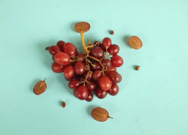 Taze tatlı, sulu, kırmızı üzümler ve yarım dilimlenmiş turkuaz bir arka plan ile bezenmiş düz bir kompozisyon.