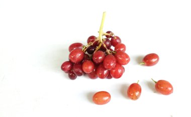 Düz kompozisyonda taze olgun tatlı sulu kırmızı üzümler beyaz bir zeminde izole edilmiş.