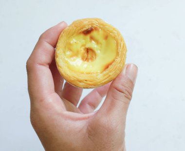 Taze yumurtalı tart fırında tatlı tatlı tatlı pasta ya da beyaz bir fon üzerinde izole edilmiş Asyalı bir kadının elinde Portekiz usulü turta..