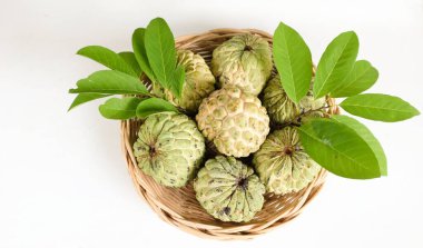 Taze yeşil kremalı elma, elma şekeri, anona cherimola (annona squamosa l.) beyaz bir arkaplanda sepetin içindeki yapraklı meyve. Tropikal egzotik meyve ve sağlıklı meyve