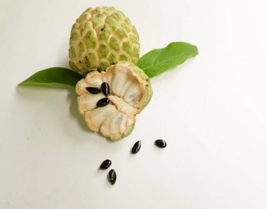 Taze olgun muhallebi, elma şekeri, çeri çiçeği (annona squamosa l.) ile bembeyaz zemin üzerinde izole edilmiş yapraklarla ikiye bölünmüş meyve içeren düz bir kompozisyon. tropikal egzotik meyve
