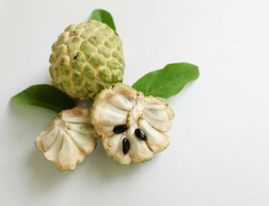 Taze olgun muhallebi, elma şekeri, çeri çiçeği (annona squamosa l.) ile bembeyaz zemin üzerinde izole edilmiş yapraklarla ikiye bölünmüş meyve içeren düz bir kompozisyon. tropikal egzotik meyve