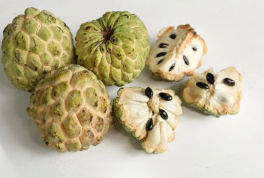 flat lay composition with fresh ripe custard apple,sugar apple, annona cherimola (annona squamosa l.) fruit cut in half sliced with leaves isolated on white backdrop. tropical exotic fruit clipart