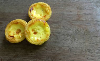 Bir yığın taze yumurtalı tart fırında tatlı tatlı tatlı pasta ya da Portekiz usulü turta izole edilmiş ahşap bir zemin üzerinde.