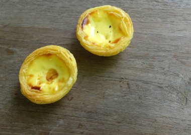 Bir yığın taze yumurtalı tart fırında tatlı tatlı tatlı pasta ya da Portekiz usulü turta izole edilmiş ahşap bir zemin üzerinde.