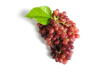 Düz kompozisyon, taze olgun tatlı sulu bütün kırmızı üzümler ve yeşil yapraklar beyaz bir arka planda izole edilmiş. Sağlıklı meyveler.