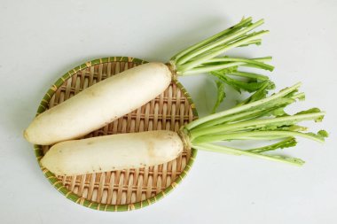 Taze beyaz daikon, daikon turp, turp, beyaz turp, (raphanus sativus var. Beyaz arka planda izole edilmiş ahşap bir sepetin üzerinde yatıyordu.