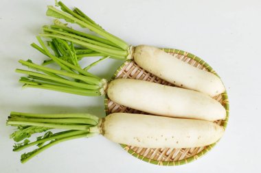 Taze beyaz daikon, daikon turp, turp, beyaz turp, (raphanus sativus var. Beyaz arka planda izole edilmiş ahşap bir sepetin üzerinde yatıyordu.