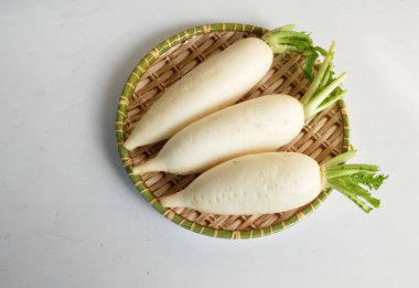 Taze beyaz daikon, daikon turp, turp, beyaz turp, (raphanus sativus var. Beyaz bir arka planda izole edilmiş ahşap bir tepside yatıyordu.