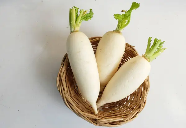 Dilimlenmiş taze beyaz daikon, daikon turp, turp, beyaz turp, (raphanus sativus var. Beyaz bir arka planda izole edilmiş ahşap bir sepetin içinde. Sağlıklı yemek için sebze hazırlıyorum.