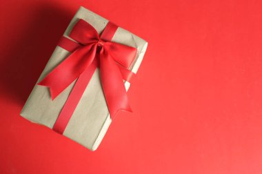  Kırmızı arkaplanda kırmızı kurdeleli bir el işi kağıt hediye kutusu. Enfes bir tebrik konsepti. Yeni yıl hediyeleri, Noel, yeni yıl hediyeleri, Noel, sevgililer günü, 