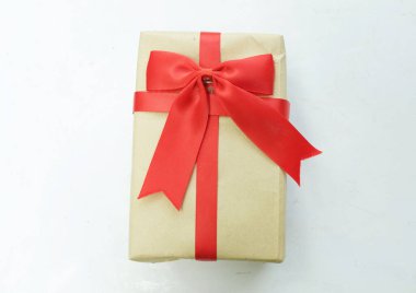 Beyaz arka planda kırmızı kurdeleli bir el işi kağıt hediye kutusu. Enfes bir tebrik konsepti. Yeni yıl hediyeleri, Noel, yeni yıl hediyeleri, Noel, sevgililer günü, 