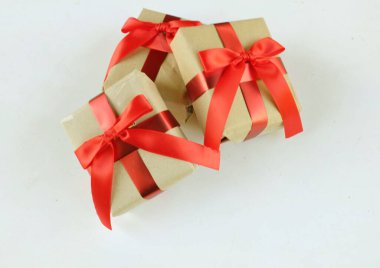 El işi kağıdına sarılı Noel hediyeleri, beyaz bir arka planda el yapımı hediyeler. Noel hediyeleri ve kırmızı Noel yayları. Bayram havasından bir hediye. Yeni yıl Noel dekoru. 