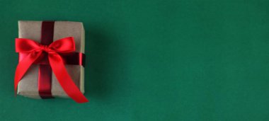 El işi kağıdına sarılı Noel hediyeleri, yeşil arka planda el yapımı hediyeler. Noel hediyeleri ve kırmızı Noel yayları. Bayram havasından bir hediye. Yeni yıl Noel dekoru. 