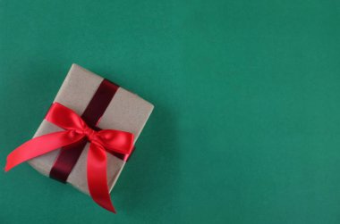 El işi kağıdına sarılı Noel hediyeleri, yeşil bir arka planda el yapımı hediyeler. Noel hediyeleri ve kırmızı Noel yayları. Bayram havasından bir hediye. Yeni yıl Noel dekoru. 